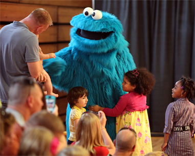 Cookie Monster, a philosophical Muppet who now enjoys cookies in addition to a well-balanced diet, comes out to greet Marine families during a USO performance of Sesame Street Live aboard Marine Corps Air Station New River, April 28. During the show, Cookie Monster gave advice to Marine families about moving away from friends.